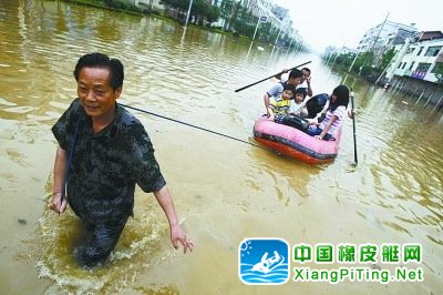  54岁的李尚其拉着一船受困群众在齐腰深的水中艰难前行，他已义务“摆渡”上百人。